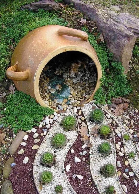 Un magnifique pot renversé en terre cuite d'où s'échappe une cascade de pétunias roses et violets dans un parterre de jardin ensoleillé.